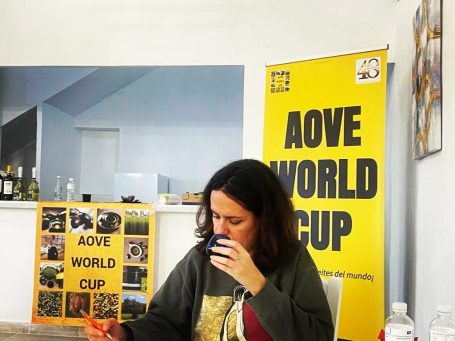 Amparo Ruiz de Adana Moreno Mujer bebiendo en un entorno con carteles del AOVE World Cup.